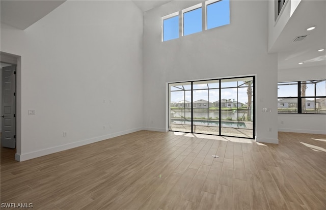 empty room with light hardwood / wood-style floors and a high ceiling