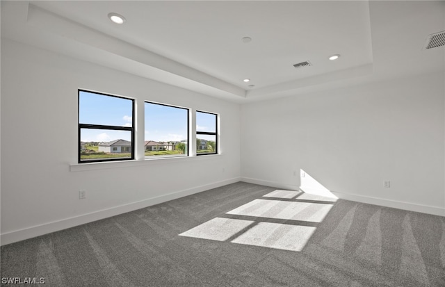 unfurnished room with dark carpet and a tray ceiling