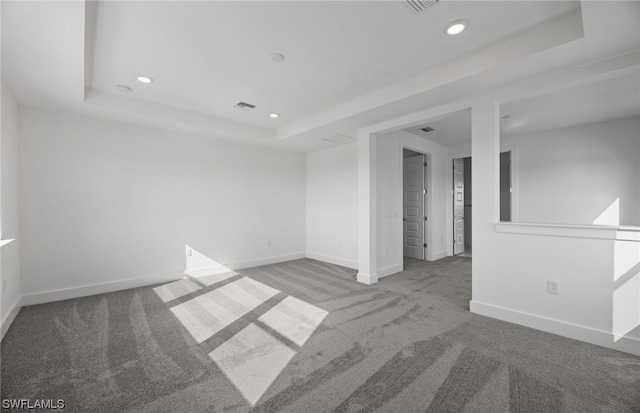 carpeted spare room featuring a tray ceiling