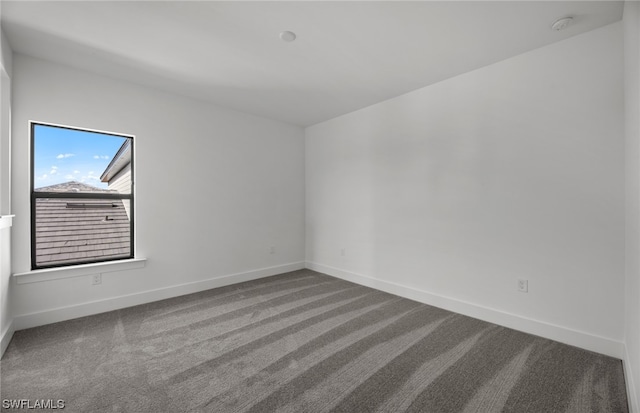 spare room with dark colored carpet