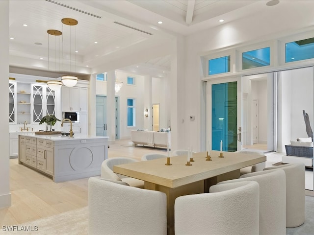 dining area featuring light hardwood / wood-style flooring, a high ceiling, and sink