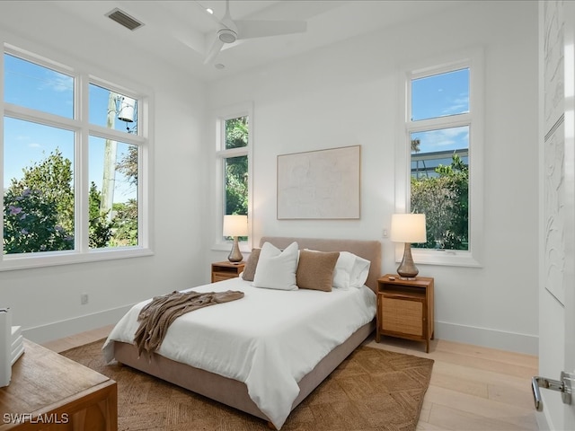 bedroom with multiple windows, ceiling fan, and light wood-type flooring