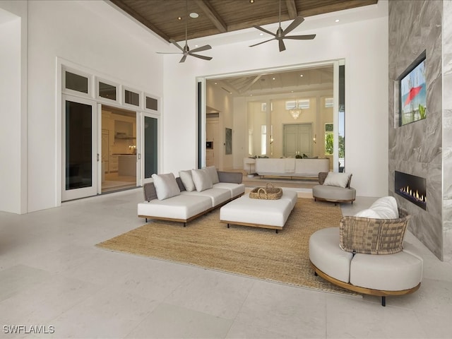 living room featuring beam ceiling, a towering ceiling, a fireplace, and wood ceiling