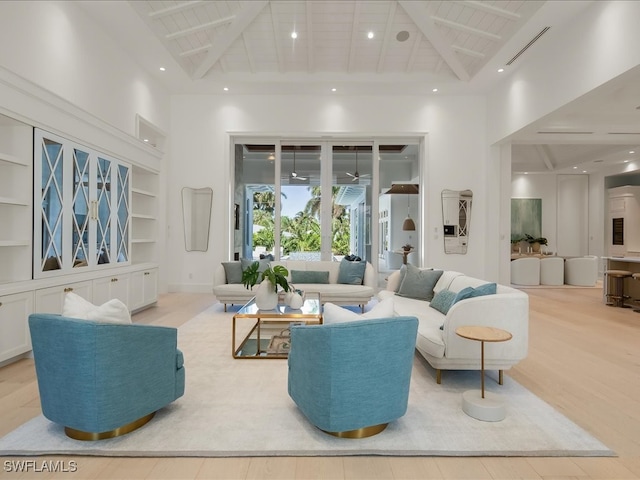 living room featuring built in features, beamed ceiling, light hardwood / wood-style floors, and high vaulted ceiling