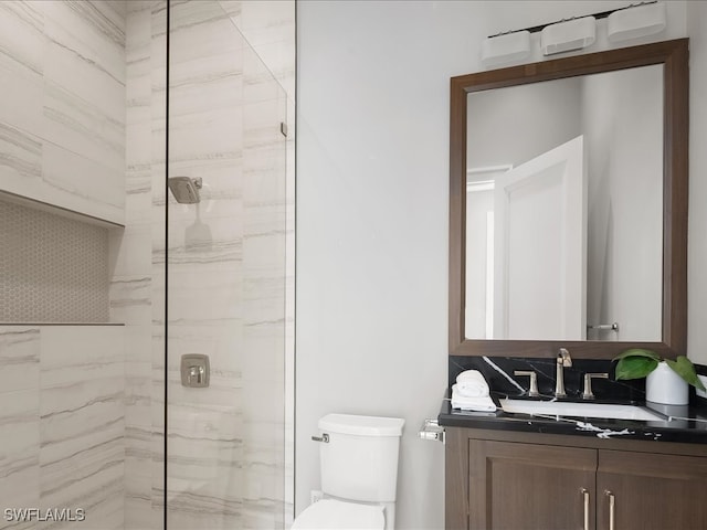 bathroom with a shower with door, vanity, and toilet