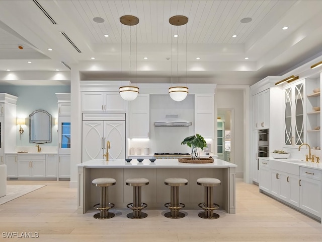 kitchen featuring paneled refrigerator, a center island, light hardwood / wood-style flooring, and hanging light fixtures