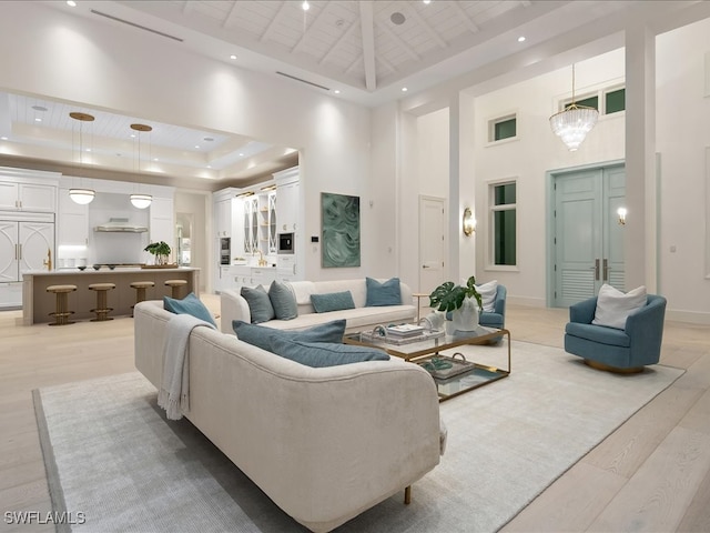 living room with a raised ceiling, light hardwood / wood-style flooring, and a high ceiling