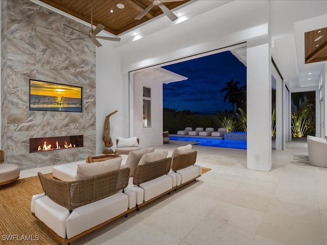 living room with beamed ceiling, ceiling fan, a premium fireplace, and wooden ceiling