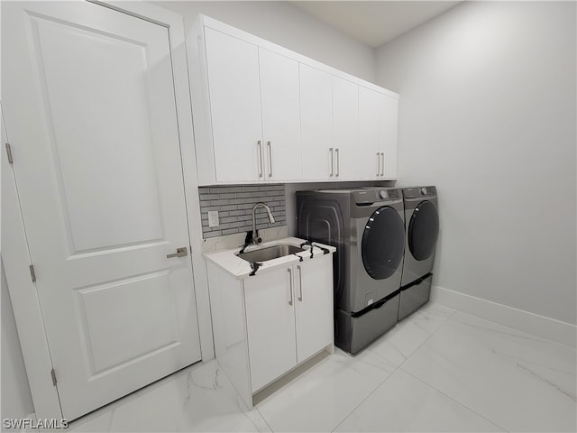 washroom featuring washing machine and clothes dryer, cabinets, and sink