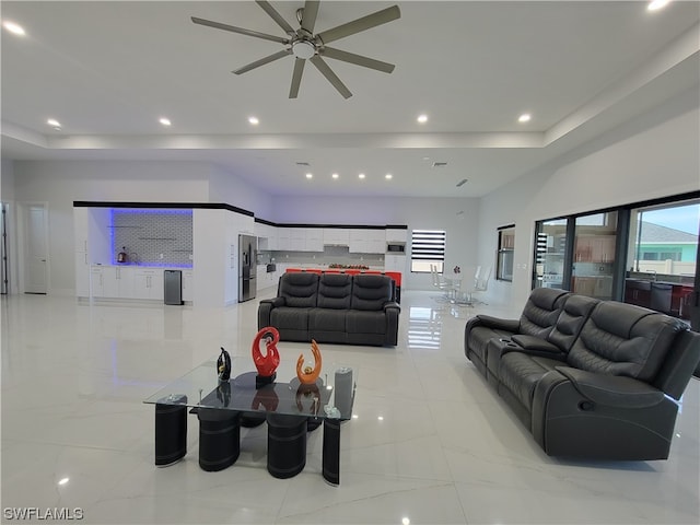 living room featuring a raised ceiling and ceiling fan