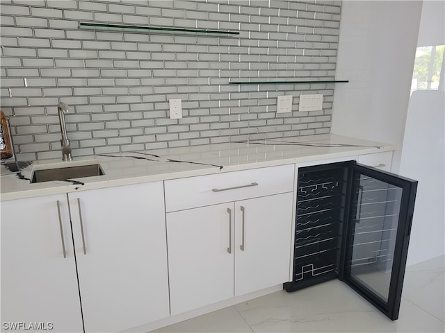 kitchen featuring wine cooler, light stone countertops, backsplash, and white cabinets