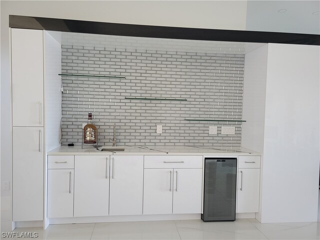 bar featuring light tile patterned floors, light stone countertops, backsplash, and white cabinets