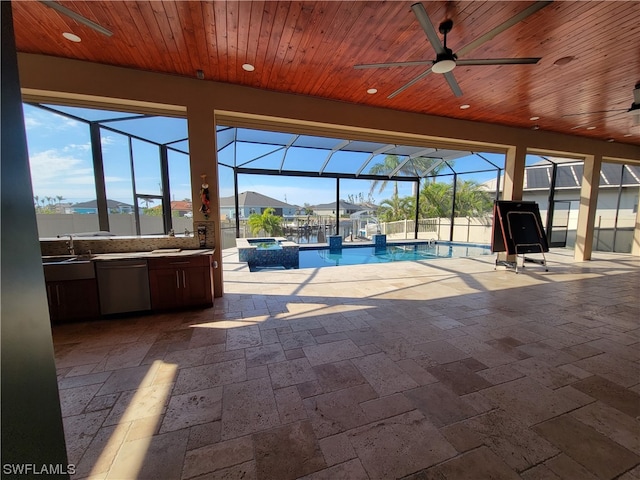 view of swimming pool with a patio area, sink, glass enclosure, ceiling fan, and an outdoor kitchen