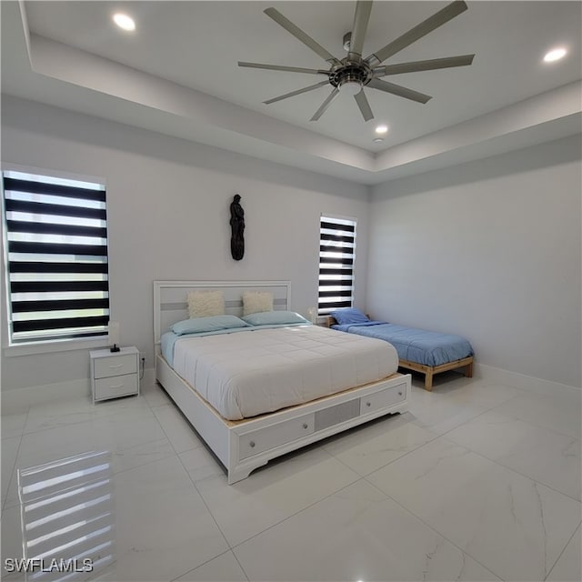 bedroom featuring a raised ceiling and ceiling fan