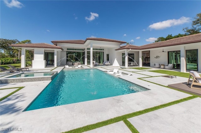 back of property with ceiling fan, a pool with hot tub, and a patio