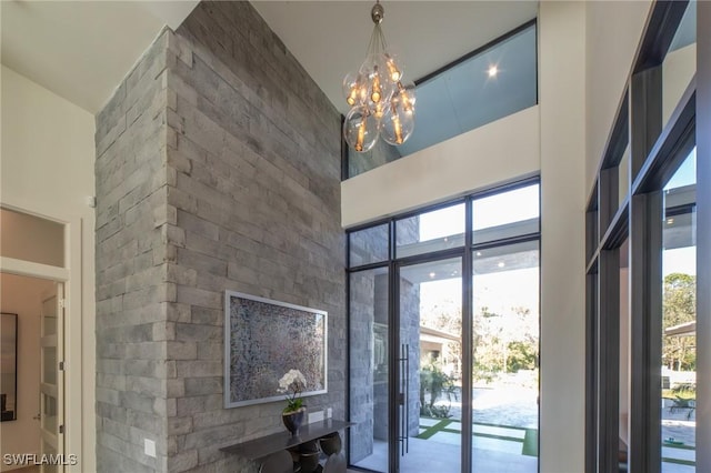 interior space featuring a healthy amount of sunlight, a chandelier, and a high ceiling