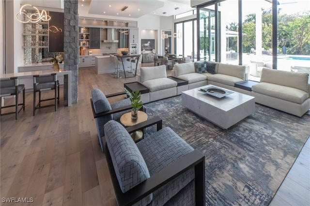 living room with a notable chandelier, dark wood-type flooring, and a wall of windows