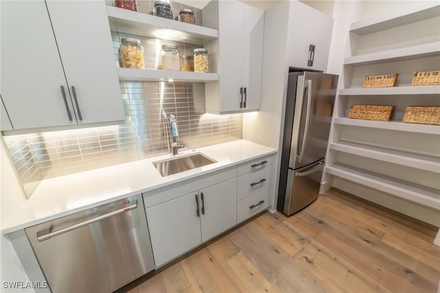 kitchen featuring sink, light wood-type flooring, white cabinets, and appliances with stainless steel finishes