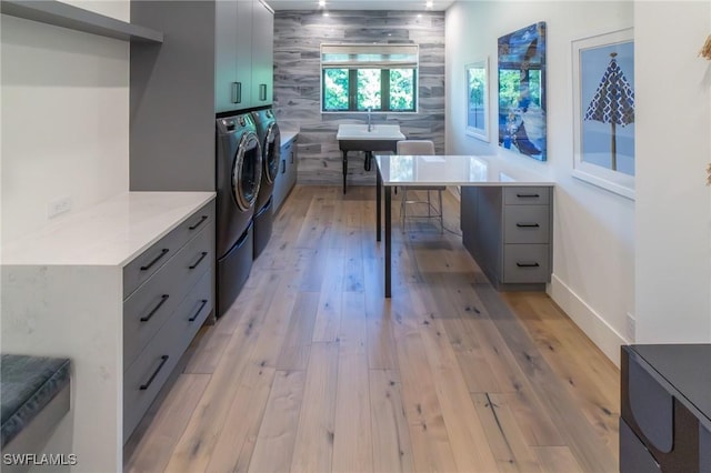 laundry room with cabinets, washing machine and dryer, sink, and light hardwood / wood-style floors