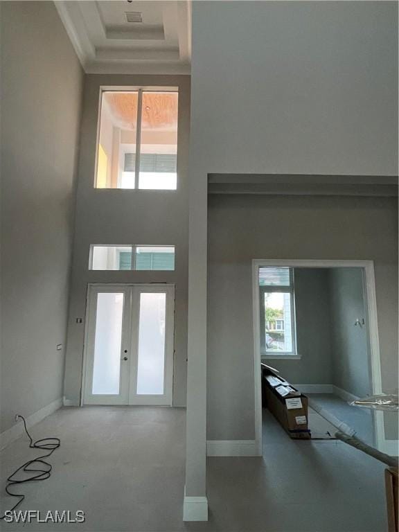 foyer featuring crown molding, a high ceiling, and french doors