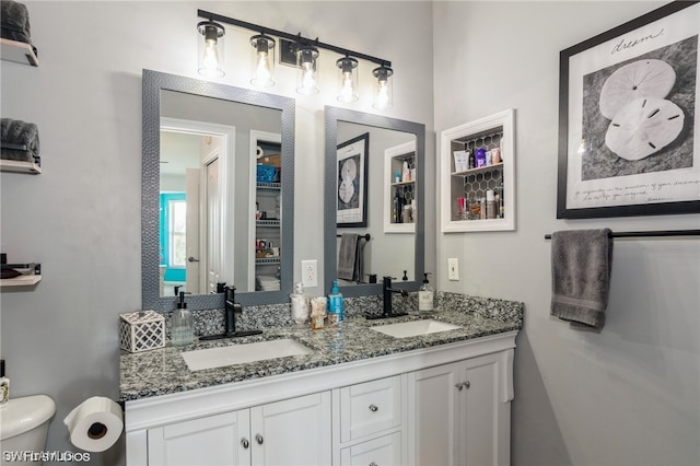 bathroom with toilet, double sink, and vanity with extensive cabinet space