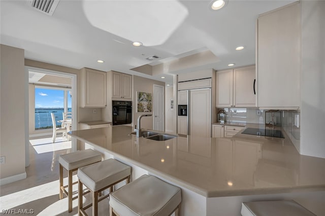 kitchen with kitchen peninsula, sink, a breakfast bar area, and black appliances