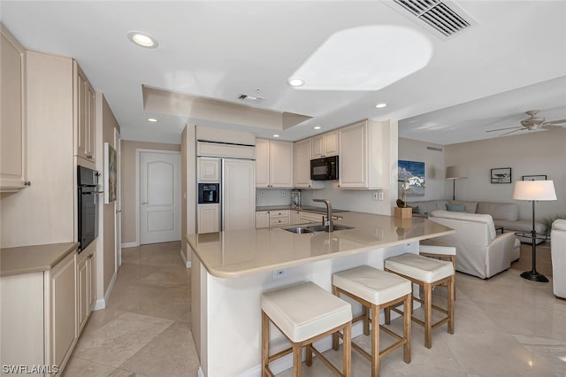 kitchen featuring sink, a breakfast bar area, black appliances, and kitchen peninsula