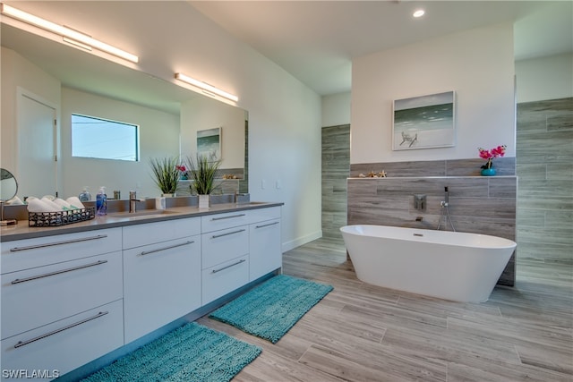 bathroom with tile walls, vanity, and a bath