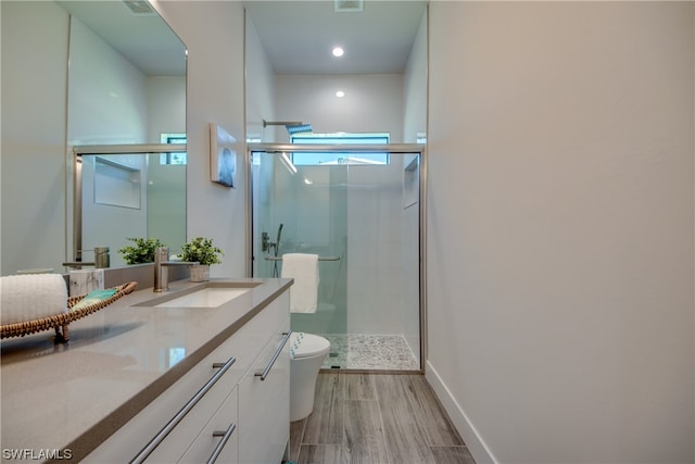 bathroom featuring a shower with door, large vanity, and toilet