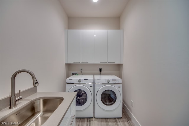 washroom with cabinets, sink, light wood-type flooring, electric dryer hookup, and washer and clothes dryer