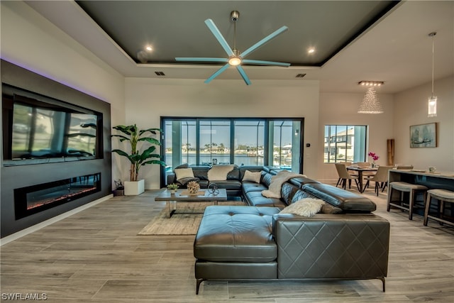 living room featuring a tray ceiling, light hardwood / wood-style floors, and ceiling fan