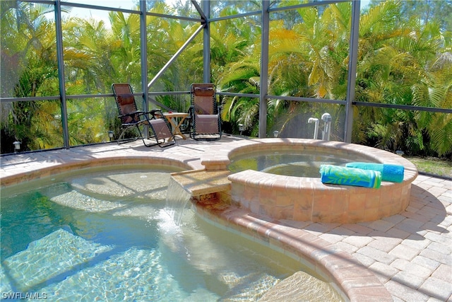 view of pool featuring an in ground hot tub, glass enclosure, and a patio area