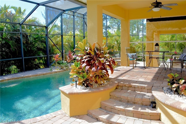 view of pool with glass enclosure, ceiling fan, and a patio