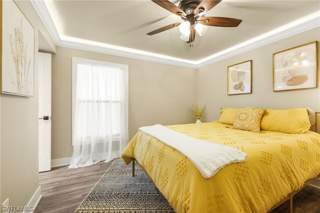 bedroom featuring multiple windows, dark hardwood / wood-style floors, ceiling fan, and ornamental molding