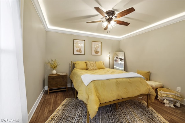 bedroom featuring a raised ceiling, ceiling fan, ornamental molding, and dark wood-type flooring