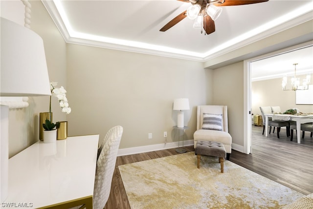 interior space with a raised ceiling, dark hardwood / wood-style flooring, ceiling fan with notable chandelier, and ornamental molding