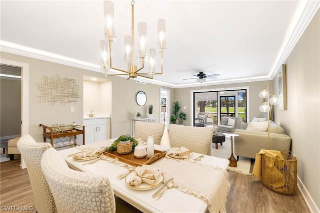 dining room with ornamental molding, ceiling fan with notable chandelier, sink, and light wood-type flooring