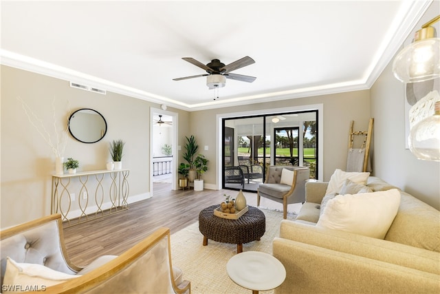 living room with hardwood / wood-style floors, crown molding, and ceiling fan