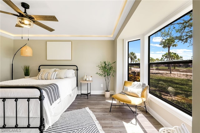 bedroom featuring a tray ceiling, ornamental molding, ceiling fan, and hardwood / wood-style flooring