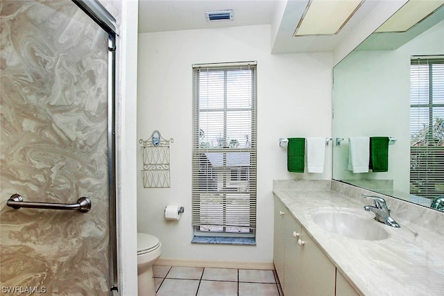 bathroom featuring a wealth of natural light, tile floors, large vanity, and toilet