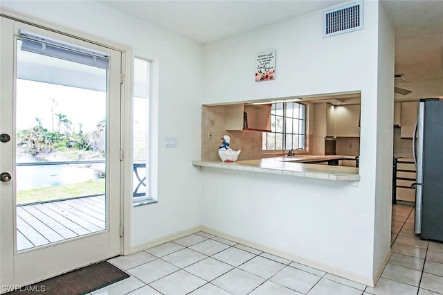 kitchen featuring stainless steel fridge, a healthy amount of sunlight, and light tile floors