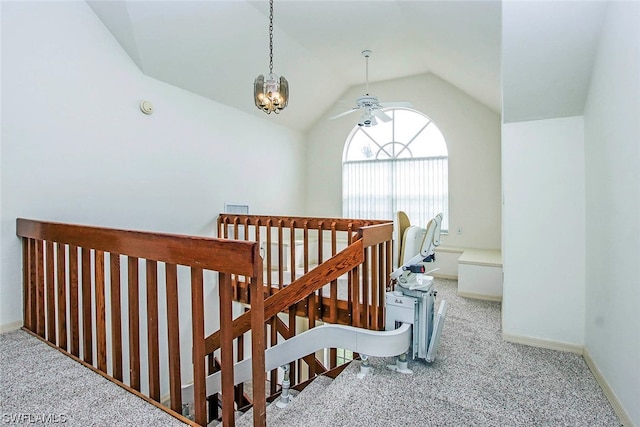 staircase featuring light carpet, vaulted ceiling, and ceiling fan with notable chandelier