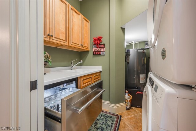 washroom featuring sink, light tile patterned floors, cabinets, electric water heater, and stacked washer / drying machine