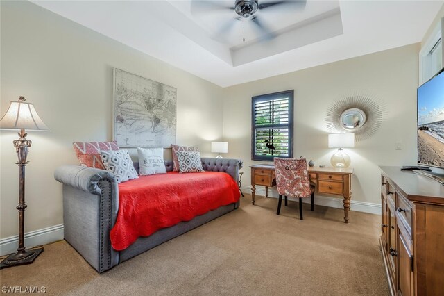 bedroom with light carpet, a tray ceiling, and ceiling fan