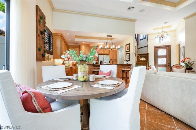 dining space featuring a notable chandelier, a tray ceiling, ornamental molding, and light tile patterned flooring