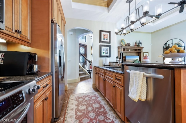 kitchen with pendant lighting, sink, stainless steel appliances, ornamental molding, and a raised ceiling