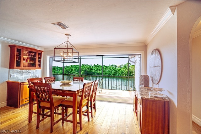 dining area with an inviting chandelier, crown molding, and light wood-type flooring