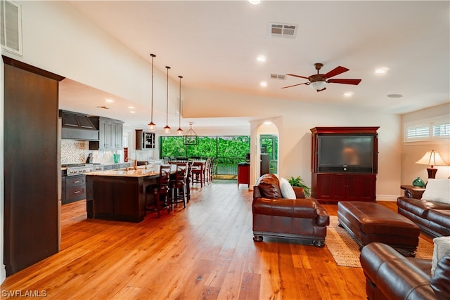 living room with high vaulted ceiling, ceiling fan, and light wood-type flooring