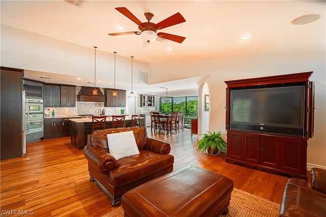 living room with vaulted ceiling, ceiling fan, and light hardwood / wood-style flooring