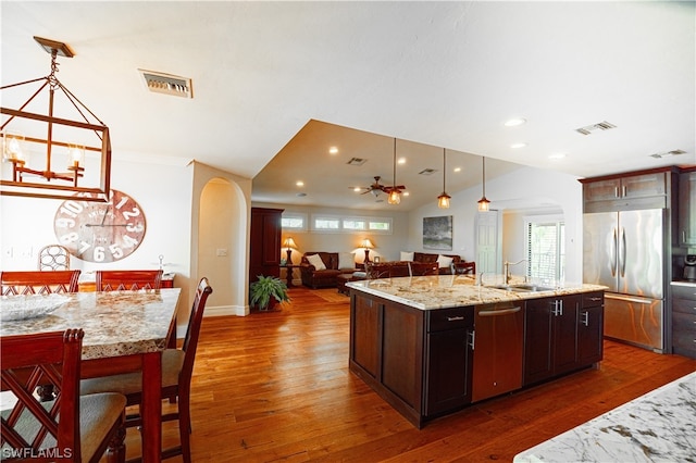 kitchen with an island with sink, pendant lighting, appliances with stainless steel finishes, dark hardwood / wood-style floors, and sink